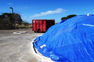 Covered stockpiles and bermed storm drains protect stormwater.