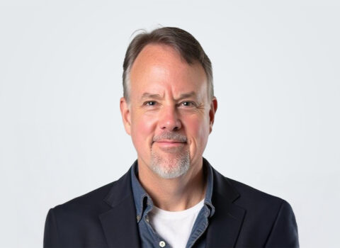 Headshot of a person in a suit jacket with a jean jacket underneath.