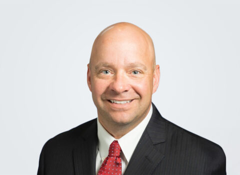 Headshot of a person in a suit with a red tie.
