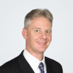 Headshot of Jeremie Maehr, a man with blond-grey hair, in front of a light grey background.