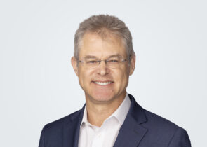 Headshot of Mark Minkowski, a man with blond-grey hair, in front of a light grey background.