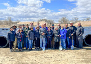 SECWCD staff stand in front of large pipes in an arid Colorado terrain.