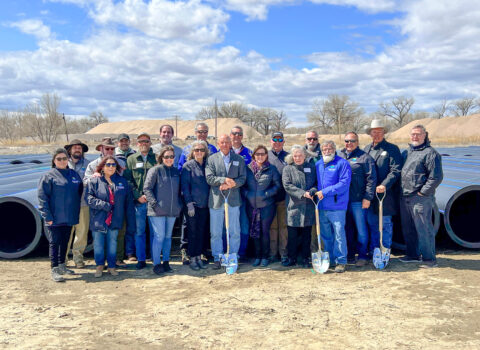 SECWCD staff stand in front of large pipes in an arid Colorado terrain.