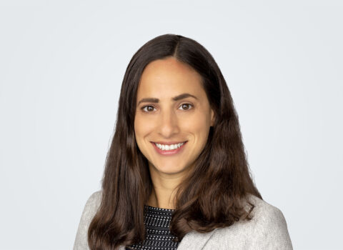 Headshot of Claudia Llerandi. A person with long brown hair in white cardigan.
