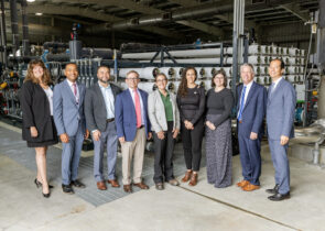 Pure Water Monterey Expansion Ribbon Cutting photo with key KJ and M1W staff posing in a row in front of the facility