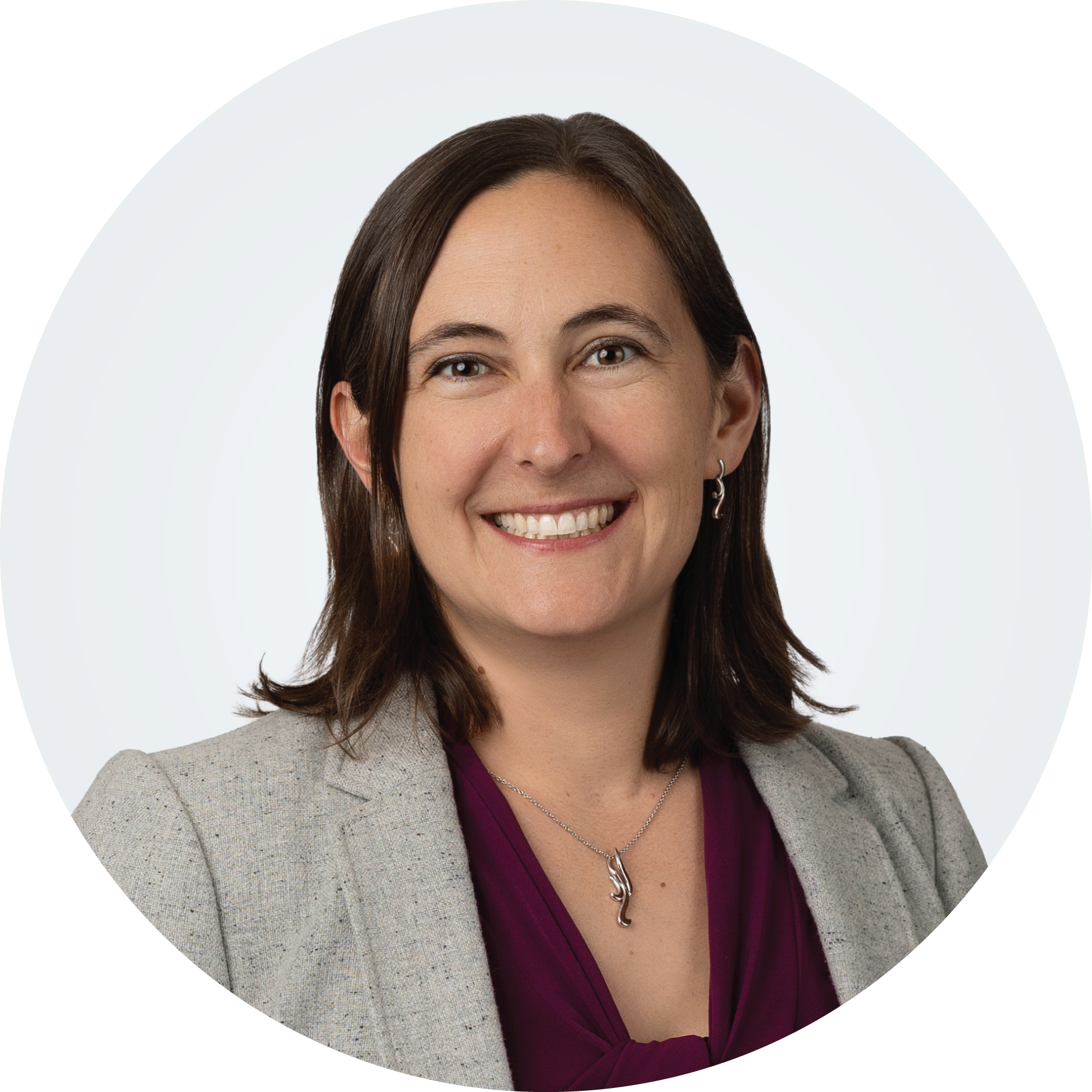Headshot of Rachelle Thompson, a person with medium-length brown hair, wearing a necklace, purple blouse, and grey blazer.
