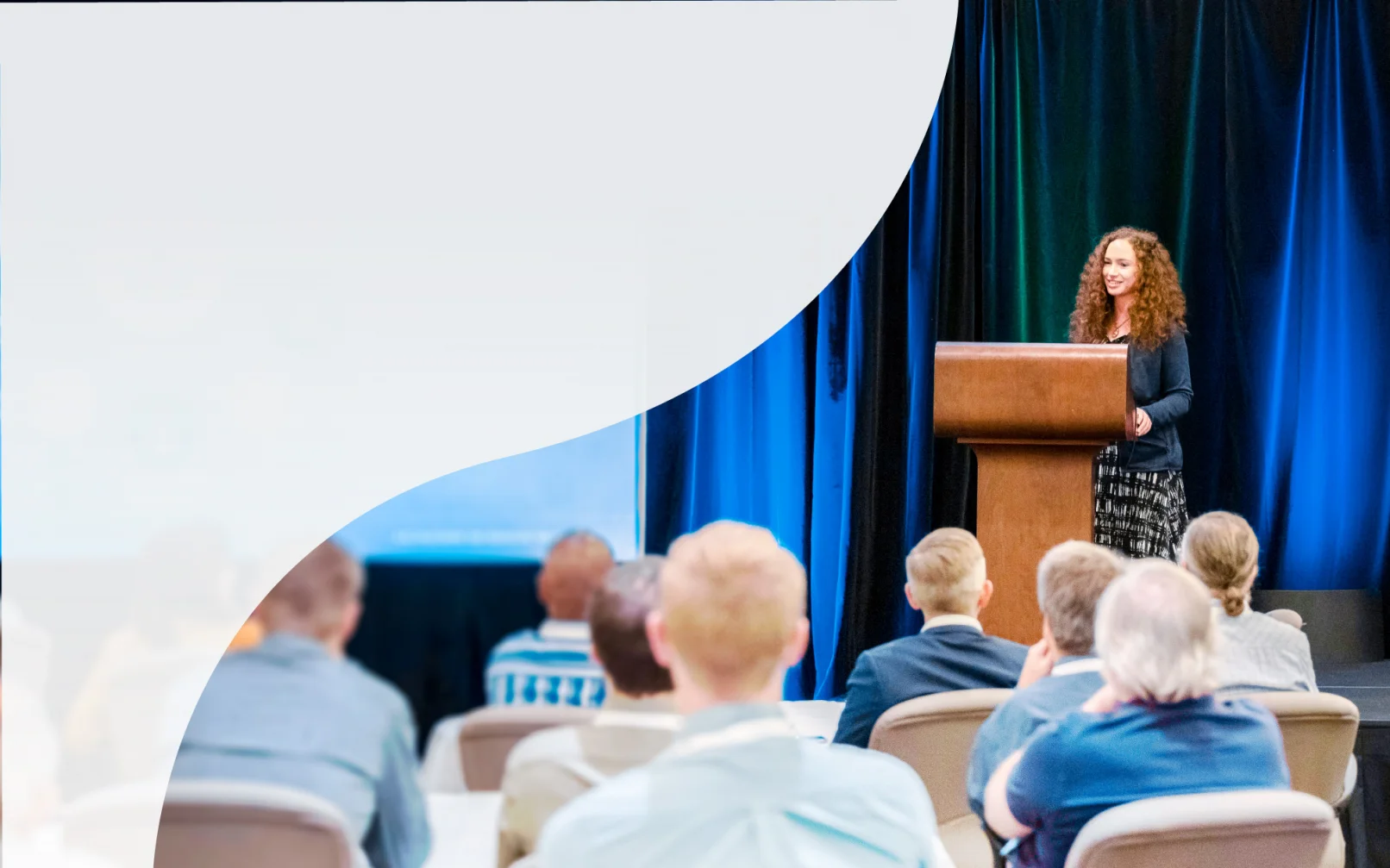 KJ employees explore a water treatment plant. The employees wear yellow hardhats, yellow and orange safety vests, are walking away from the camera, and surrounded by white and grey pipe structures.