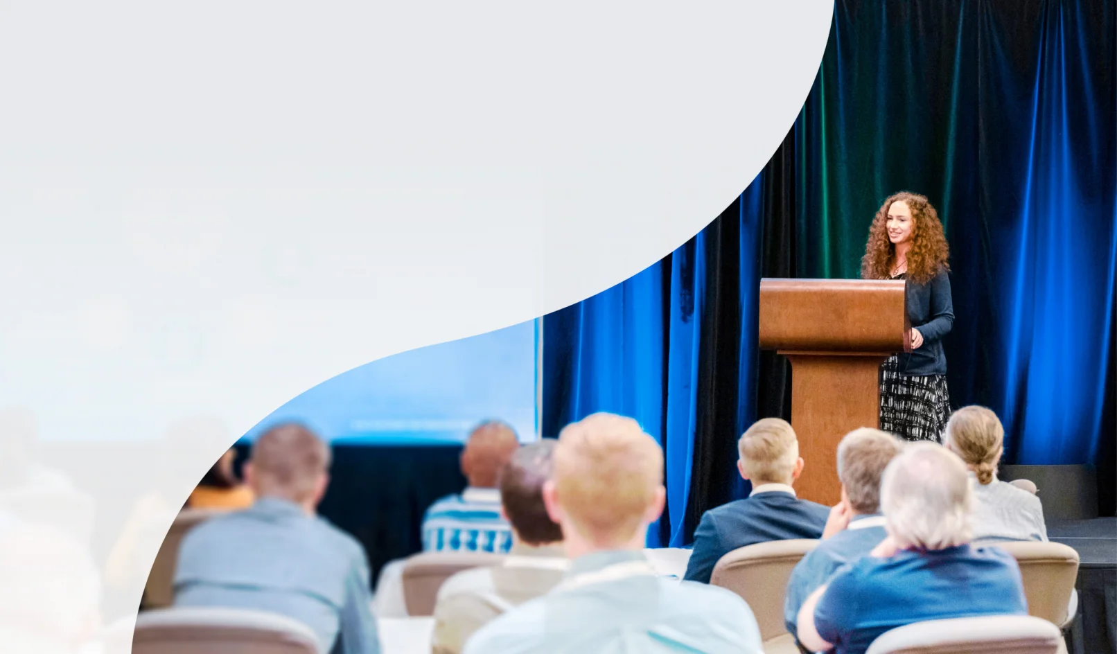KJ employees explore a water treatment plant. The employees wear yellow hardhats, yellow and orange safety vests, are walking away from the camera, and surrounded by white and grey pipe structures.